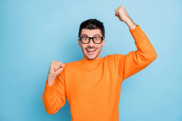 Foto de joven feliz sonrisa positiva celebrar victoria victoria suerte éxito puños manos aisladas sobre fondo de color azul —  Fotos de Stock