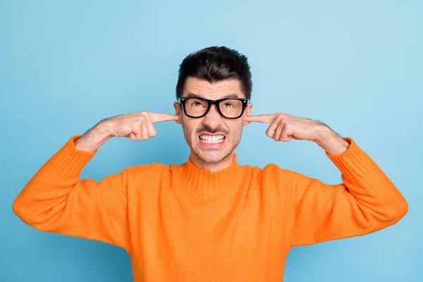 Foto de furia negativa guapo chico sonreír dientes dedos cerrar las orejas buscar espacio vacío aislado sobre fondo de color azul — Foto de Stock