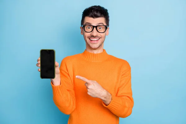 Foto de chico guapo asombrado indican dedo teléfono pantalla sonrisa toothy aislado en fondo de color azul — Foto de Stock