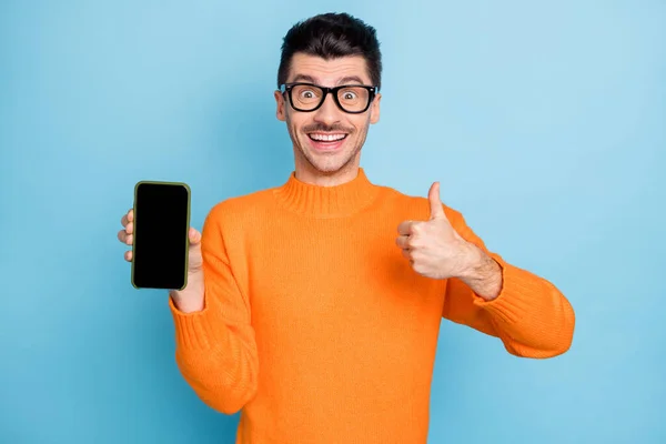 Foto de joven emocionado hombre feliz sonrisa positiva mantenga el teléfono celular mostrar pulgar-up anuncio recomiendan sugerir aislado sobre fondo de color azul — Foto de Stock