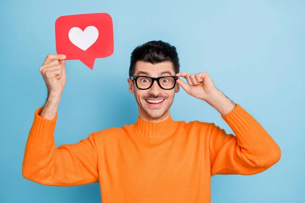 Foto di stupito persona allegra tenere il cuore come carta di carta touch occhiali isolato su sfondo di colore blu — Foto Stock