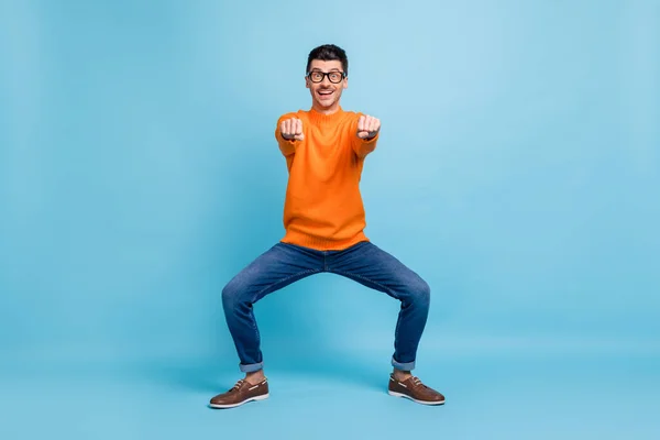 Volledige lengte foto van leuke kerel dansen spelen handen vuisten vooruit tandenachtige glimlach geïsoleerd op blauwe kleur achtergrond — Stockfoto