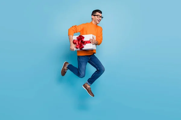 Full-Size-Profilfoto von positiv erstaunt Mann beeilen halten Geschenkbox isoliert auf blauem Hintergrund — Stockfoto