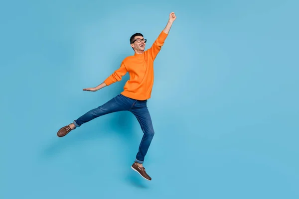 Foto de perfil de corpo inteiro de pessoa impressionada punho para cima salto olhar espaço vazio isolado no fundo de cor azul — Fotografia de Stock