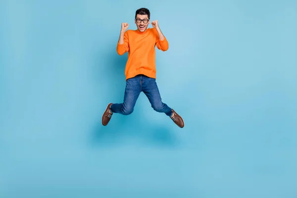 Retrato de corpo inteiro de cara bonito impressionado pular punhos altos para cima comemorar isolado no fundo de cor azul — Fotografia de Stock