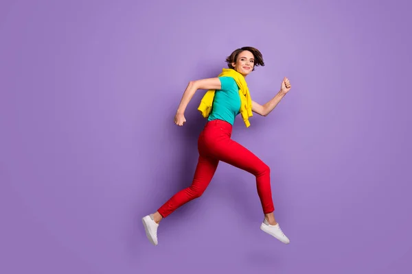 Teljes hosszúságú fotó lány ugrás futás kopás kötött pulóver póló nadrág tornacipő elszigetelt ibolya szín háttér — Stock Fotó