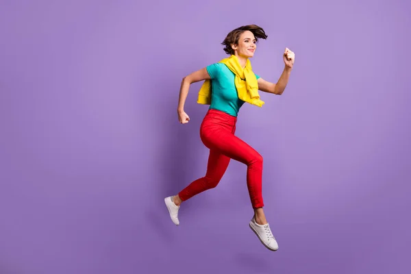 Full längd profil foto av sportig flicka hoppa springa slitage knutna tröja t-shirt byxor sneakers isolerad violett färg bakgrund — Stockfoto