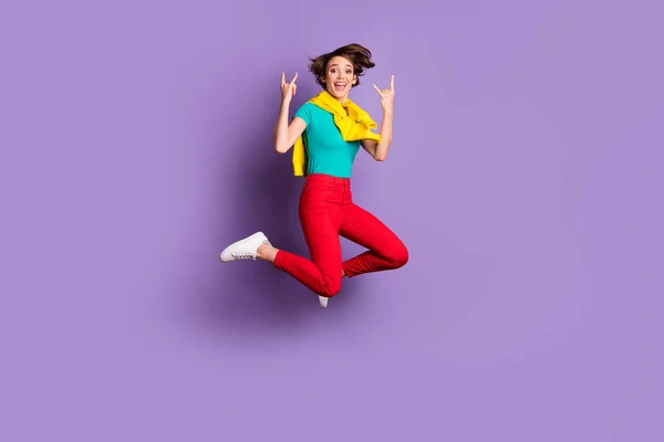 Volledige lengte foto van meisje springen verhogen hoorns teken slijtage gebonden pullover t-shirt broek schoenen geïsoleerde violette kleur achtergrond — Stockfoto