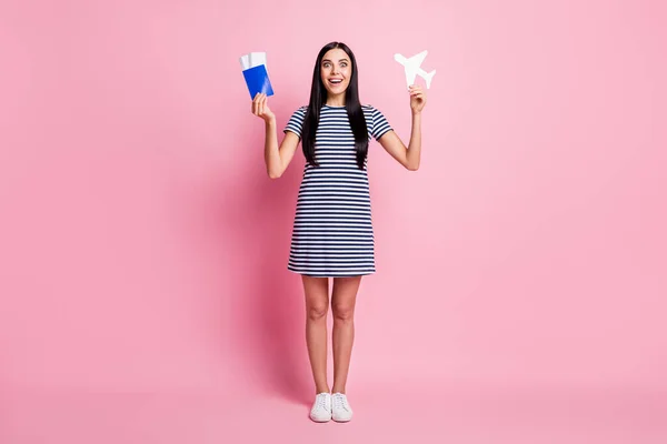 Tamanho do corpo de comprimento total vista de menina encantadora alegre surpreendido segurando na mão documentos de cartão de avião se divertindo isolado sobre fundo cor pastel rosa — Fotografia de Stock