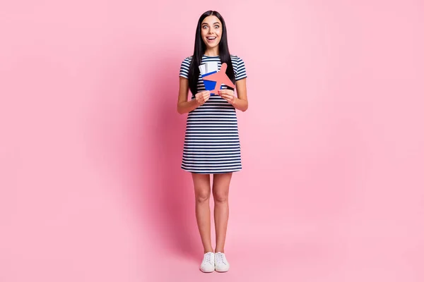 Tamanho do corpo de comprimento total vista de menina muito alegre espantado segurando na mão documentos de cartão de avião que vão para o exterior isolado no fundo cor pastel rosa — Fotografia de Stock