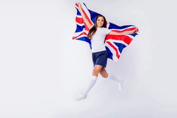 Full size photo of positive girl soccer fan enjoy her favorite team score goal on world final football cup jump hold british flag wear boots socks isolated over gray color background Royalty Free Stock Images