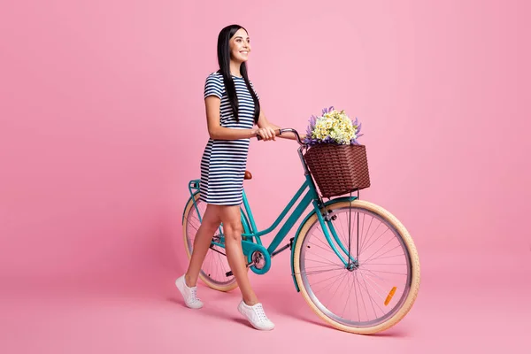 Ganzkörpergröße Profil Seitenansicht von charmanten fröhlichen Mädchen zu Fuß Fahrrad verbringen Zeit frische Luft isoliert auf rosa Pastellfarbe Hintergrund — Stockfoto