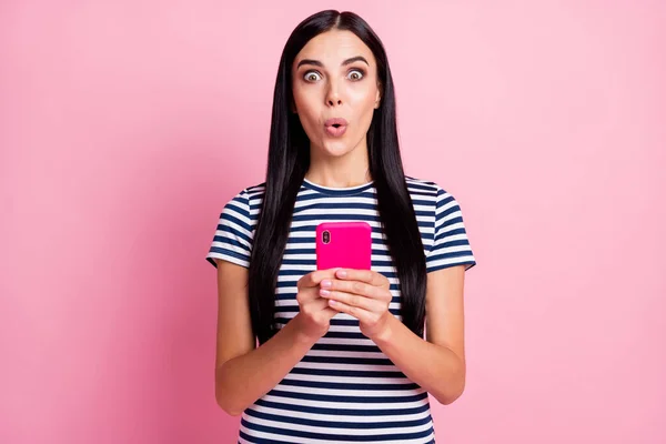 Foto portret van onder de indruk vrouw met telefoon in twee handen geïsoleerd op pastel roze gekleurde achtergrond — Stockfoto