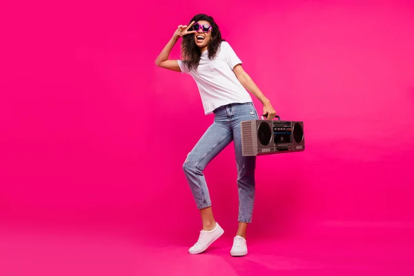 Фотографія повного розміру смішної леді тримає бум коробки шоу v-знак одягу окуляри футболки джинси кросівки ізольовані на рожевому фоні — стокове фото