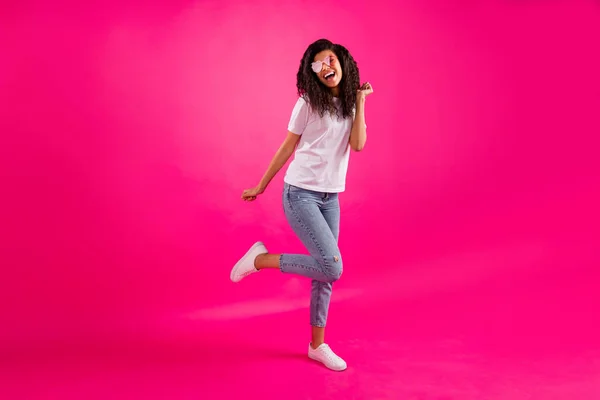 Фотографія повного розміру смішної молодої леді танцю носить окуляри футболки джинси кросівки ізольовані на фоні рожевого кольору — стокове фото
