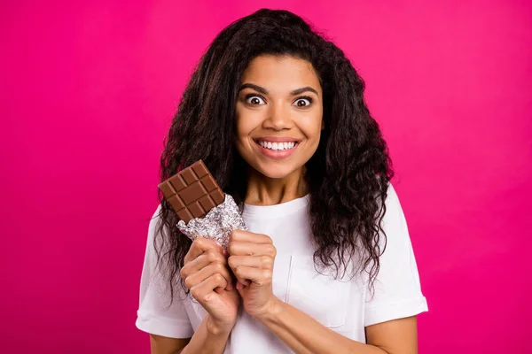 Foto van verbaasd brunette jonge dame willen chocolade dragen wit t-shirt geïsoleerd op roze kleur achtergrond — Stockfoto