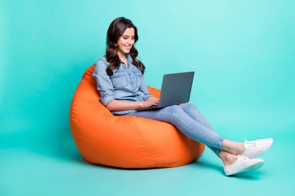 Foto panjang penuh dari wanita muda positif yang menawan duduk diam tas kacang kerja laptop terisolasi pada latar belakang warna teal — Stok Foto