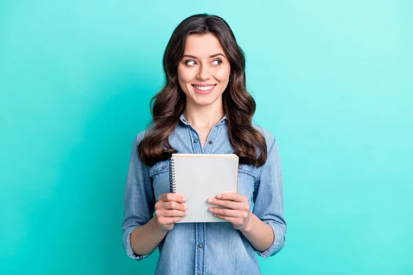 Foto di lucido bella giovane signora vestita camicia di jeans sorridente in possesso di copybook cercando spazio vuoto isolato colore verde acqua sfondo — Foto Stock