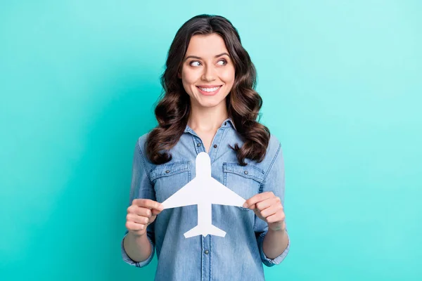 Foto de menina feliz sorriso positivo segurar papel avião sonho viagem olhar espaço vazio isolado sobre fundo cor teal — Fotografia de Stock