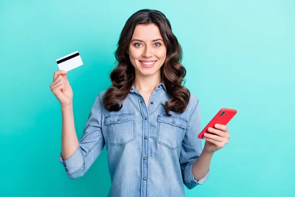 Foto de niña feliz sonrisa positiva celebrar compras tarjeta bancaria onling teléfono inteligente aislado sobre fondo de color verde azulado —  Fotos de Stock