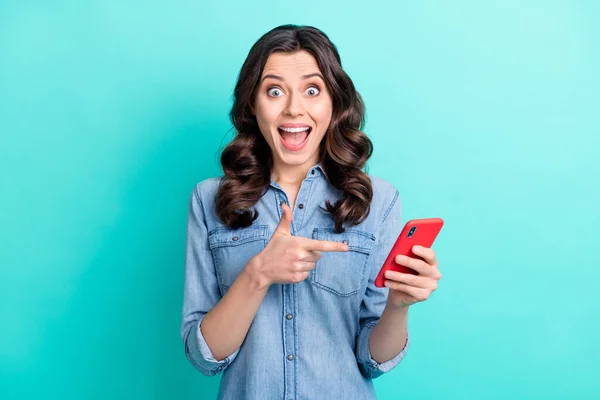 Foto van geluk onder de indruk jonge vrouw dragen jeans shirt wijzende vinger modern apparaat glimlachen geïsoleerde turquoise kleur achtergrond — Stockfoto
