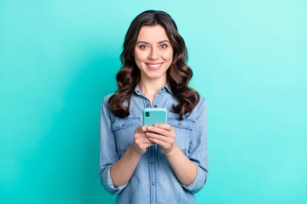 Foto van zoete schattige jonge dame gekleed denim shirt typen moderne inrichting geïsoleerde teal kleur achtergrond — Stockfoto