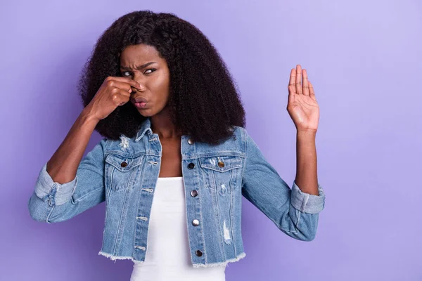 Foto de joven infeliz disgustada mujer africana cubierta cerrar nariz mal olor no muestran ningún signo aislado en el fondo de color púrpura —  Fotos de Stock
