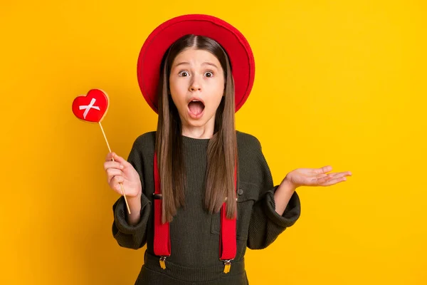 Foto portret van verbaasd meisje houden hartvormige cookie verrast misverstand geïsoleerde levendige gele kleur achtergrond — Stockfoto