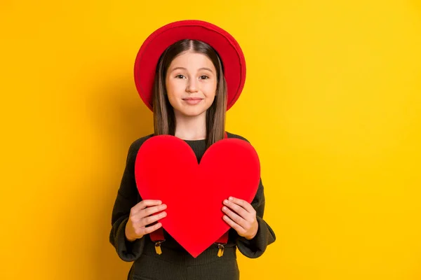 Foto retrato de menina linda mantendo coração vermelho em forma de cartão postal no dia dos namorados isolado cor amarela vívida fundo — Fotografia de Stock