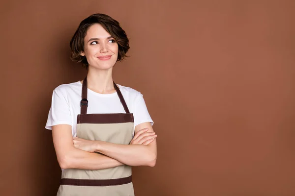 Foto di felice sognante bella ragazza con le braccia piegate proprietario del negozio di caffè guardare copyspace isolato su sfondo di colore marrone — Foto Stock