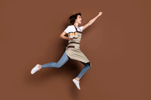 Full length body size view of beautiful cheerful girl bringing coffee jumping striving striving success isolated over brown color background — стоковое фото