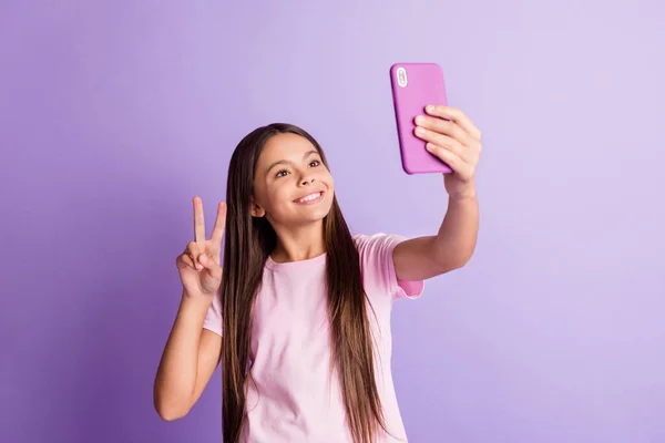 Foto de encantadora colegial bonito vestido t-shirt tacking selfie dispositivo moderno mostrando v-sinal isolado cor roxa fundo — Fotografia de Stock