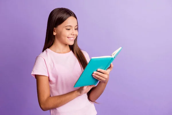 魅力的な光沢のある若い女の子の写真を着てピンクtシャツ笑顔読書本孤立した紫色の背景 — ストック写真