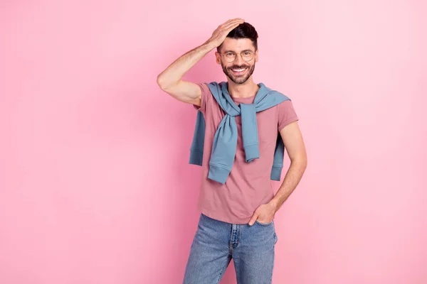 Foto di bello giovane affascinante uomo tenere mano capelli tasca jeans isolato su sfondo rosa pastello — Foto Stock