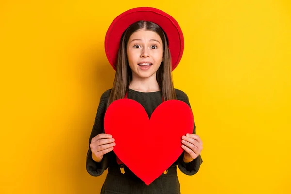 Foto retrato de menina pequena mostrando coração vermelho em forma de cartão postal no dia dos namorados isolado cor amarela brilhante fundo — Fotografia de Stock