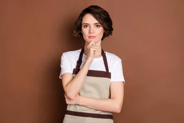 Фото молодой красивой серьезной женщины владелец кофейни думает мозговой штурм изолирован на коричневом фоне — стоковое фото