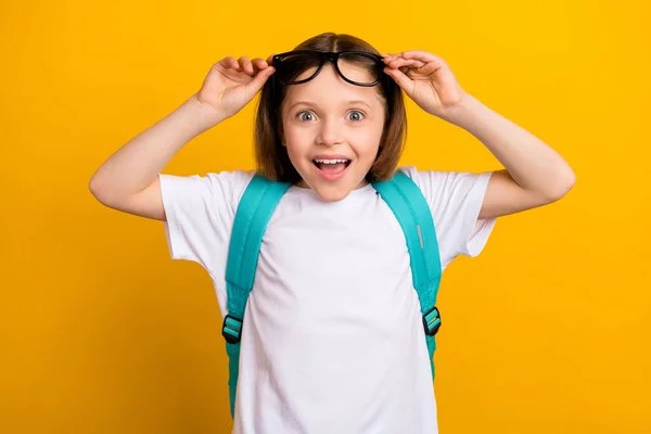 Foto retrato pequena estudante sorrindo olhando espantado boca aberta saco azul isolado cor amarela brilhante fundo — Fotografia de Stock