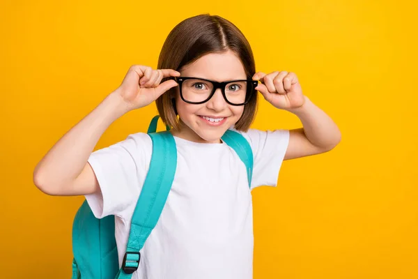 Foto ritratto piccola studentessa sorridente indossare occhiali blu zaino isolato vivido colore giallo sfondo — Foto Stock