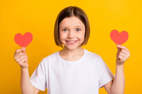 Foto retrato menina bob hairdress mostrando coração cartões postais no dia dos namorados isolado vibrante cor amarela fundo — Fotografia de Stock