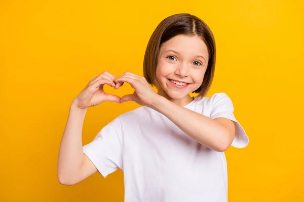 Foto retrato menina bob hairdress mostrando coração com as mãos isoladas vibrante cor amarela fundo — Fotografia de Stock