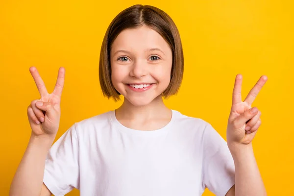 Foto retrato menina com bob hairdress sorrindo mostrando paz v-sinal isolado vibrante cor amarela fundo — Fotografia de Stock