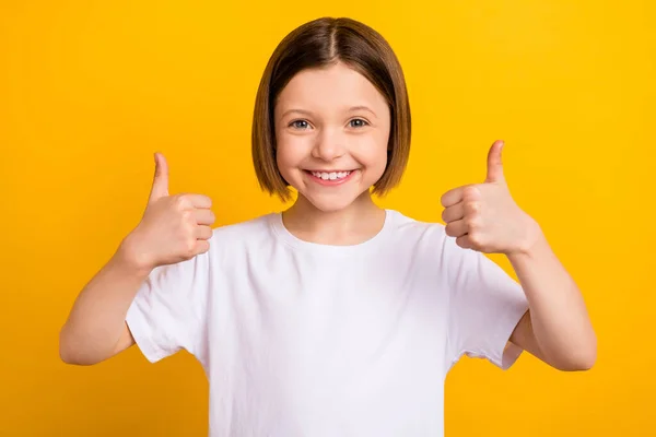 Foto retrato menina com bob hairdress sorrindo mostrando gesto de polegar para cima isolado vibrante cor amarela fundo — Fotografia de Stock