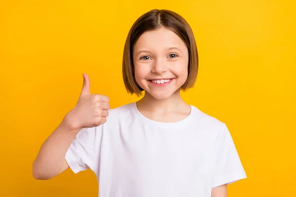 Foto retrato menina com bob hairdress sorrindo mostrando sinal de polegar para cima isolado vibrante cor amarela fundo — Fotografia de Stock