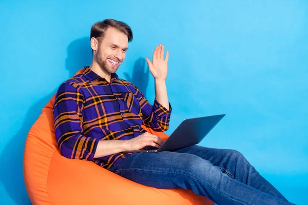 Profil portrait de l'homme positif assis chaise douce parler chat vidéo bras vague de palme isolé sur fond de couleur bleue — Photo