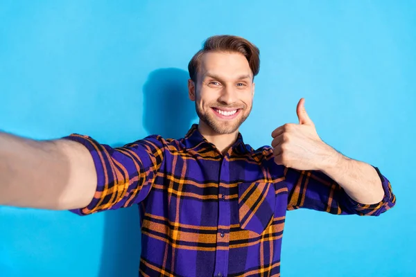 Retrato de atractivo chico alegre con camisa a cuadros que muestra dar pulgar aislado sobre fondo de color azul vivo — Foto de Stock