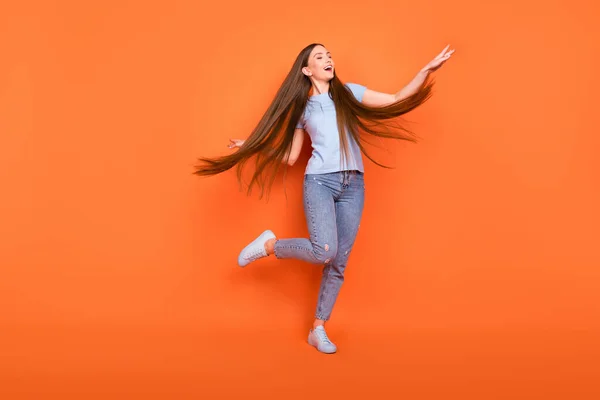 Foto de corpo inteiro de linda jovem longo penteado senhora dança desgaste azul t-shirt jeans isolado no fundo cor de laranja — Fotografia de Stock