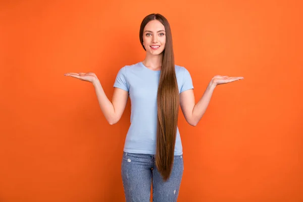 Foto van optimistisch lang kapsel jonge dame houden lege ruimte dragen blauw t-shirt geïsoleerd op oranje kleur achtergrond — Stockfoto