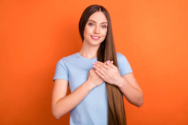 Foto de alegre peinado largo joven dama cogida de la mano llevar camiseta azul aislado en fondo de color naranja vivo — Foto de Stock