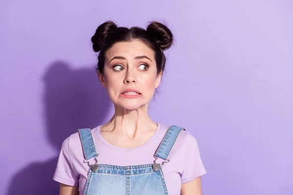 Photo of impressed guilty young woman dressed denim overall looking empty space isolated purple color background