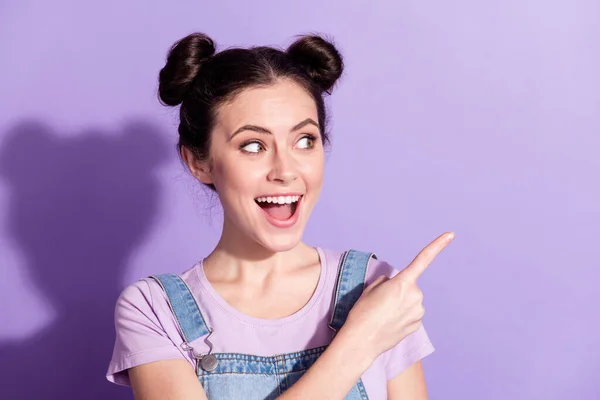 Fotografie mladé atraktivní dívka šťastný úsměv ukazováček prázdný prostor reklama promo poradenství prodej izolované přes fialové barvy pozadí — Stock fotografie